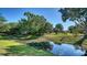 Scenic view of a tranquil pond reflecting the surrounding lush greenery and clear blue sky on a sunny day at 2385 Tall Oak Ct, Sarasota, FL 34232