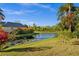 Scenic backyard view with a serene pond, lush landscaping, and colorful tropical flowers at 3390 Yonge Ave # 41, Sarasota, FL 34235