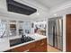 Open kitchen area with stainless steel fridge, island cooktop, and view to the patio and living area at 448 58Th St, Sarasota, FL 34243