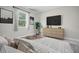 Relaxing bedroom features natural light, a modern bed and a six-drawer dresser with wall-mounted television at 5454 Rhapsody Ave, North Port, FL 34288