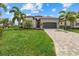 Inviting single-Gathering home with a lush green lawn, palm trees, and a brick-paved driveway leading to a gray garage at 5811 Brandon Run, Bradenton, FL 34211