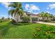 Beautifully landscaped front yard with a well-maintained lawn, colorful flowers, and a gray single-story home with palm trees at 5811 Brandon Run, Bradenton, FL 34211