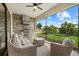 Outdoor screened patio with a built-in kitchen featuring a grill, stylish seating with a ceiling fan, and lush landscaping at 5811 Brandon Run, Bradenton, FL 34211