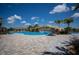 Community pool with a waterfall, lounge chairs, and palm trees, under a bright blue sky with scattered clouds at 5917 Cessna Run, Lakewood Ranch, FL 34211