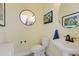 The powder room has a pedestal sink, round mirror, and neutral color palette at 5917 Cessna Run, Lakewood Ranch, FL 34211