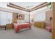 Well-lit bedroom with a tray ceiling, carpet, and wooden furniture with unique shuttered windows at 6210 Laurel Creek Trl, Ellenton, FL 34222
