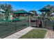 A fenced playground featuring climbing structures and covered play areas for ' entertainment at 6210 Laurel Creek Trl, Ellenton, FL 34222