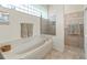 Luxurious bathroom features a soaking tub, tiled shower, and ample natural light from glass block window at 686 Silk Oak Dr, Venice, FL 34293