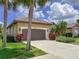 Beautiful single-story home with a well-manicured lawn, palm trees and a driveway under a bright blue sky at 686 Silk Oak Dr, Venice, FL 34293