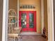 Home's front entrance featuring decorative elements, a tiled porch, and bright red double doors at 686 Silk Oak Dr, Venice, FL 34293