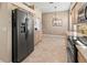 Open kitchen with stainless steel refrigerator, tiled floors, and decorative hanging light at 686 Silk Oak Dr, Venice, FL 34293