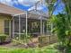 Close-up of a screened patio with a partial view of the backyard, enhanced by tropical landscaping at 686 Silk Oak Dr, Venice, FL 34293