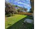 Spacious, grassy backyard featuring a privacy fence, mature trees, and clear blue skies above at 835 Indiana Ln, Sarasota, FL 34234
