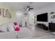Bright living room featuring sleek flooring, a comfortable gray couch, and a large television at 10459 Ladybug Cove, Parrish, FL 34219