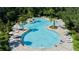 Aerial view of a large community pool surrounded by palm trees, lounge chairs, and tables with umbrellas at 10459 Ladybug Cove, Parrish, FL 34219