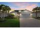 Charming single-story home with a well-manicured lawn and paver driveway during sunset at 11420 Golden Bay Pl, Bradenton, FL 34211