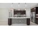 Modern kitchen featuring a central island with unique tiling, dark cabinets, and stainless steel appliances at 11420 Golden Bay Pl, Bradenton, FL 34211