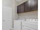 Well-lit laundry room featuring a white washer and dryer set and dark cabinets for ample storage space at 11420 Golden Bay Pl, Bradenton, FL 34211