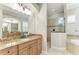 Bright bathroom featuring granite counters, wood cabinets, walk-in shower, and tub at 13107 Bridgeport Xing, Lakewood Ranch, FL 34211