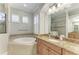 Well-lit bathroom featuring granite countertops, wood cabinets, tub and walk-in shower at 13107 Bridgeport Xing, Lakewood Ranch, FL 34211