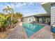 Outdoor pool with brick patio is surround by tropical plants. A covered patio is nearby at 1320 Magellan Dr, Sarasota, FL 34243
