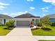 Charming single-story home featuring manicured landscaping, a two-car garage, and a welcoming entrance at 13487 Old Creek Ct, Parrish, FL 34219
