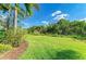 Expansive backyard with lush green grass, mature trees, and manicured landscaping at 135 River Enclave Ct, Bradenton, FL 34212