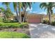 Charming single-story home featuring a tile roof, brick driveway, and tropical landscaping at 135 River Enclave Ct, Bradenton, FL 34212