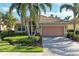 Charming single-story home featuring a tile roof, brick driveway, and tropical landscaping at 135 River Enclave Ct, Bradenton, FL 34212