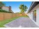 A green backyard with a brick patio, a tall wooden fence, and an attached house to the right at 1406 N Riverhills Dr, Temple Terrace, FL 33617