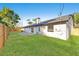 Spacious backyard with green grass, a brick patio, and a white brick house at 1406 N Riverhills Dr, Temple Terrace, FL 33617