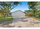 Wide exterior angle of a home, with a large driveway, three car garage, a manicured lawn, and lots of shade trees at 1406 N Riverhills Dr, Temple Terrace, FL 33617