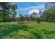 Lush green backyard featuring a scenic pond surrounded by mature trees and manicured lawn at 14404 18Th E Pl, Bradenton, FL 34212