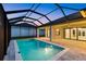 A screened-in pool illuminated at twilight with access to the home through sliding glass doors at 193 Rotonda N Blvd, Rotonda West, FL 33947