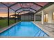 A screened-in pool features cool blue water and stylish tile against a colorful sunset sky at 193 Rotonda N Blvd, Rotonda West, FL 33947