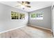 Bright bedroom with light-wood-look flooring and two windows offering views of the surrounding greenery at 2225 Alice Rd, Sarasota, FL 34231