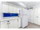 Bright kitchen features white cabinets, countertops, a blue backsplash and stainless appliances at 2225 Alice Rd, Sarasota, FL 34231