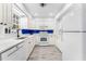 Bright kitchen features white cabinets, countertops, a blue backsplash and stainless appliances at 2225 Alice Rd, Sarasota, FL 34231