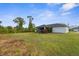 Extensive backyard with a lush green lawn, mature trees, and a screened-in lanai for outdoor relaxation at 2665 Chipley Ave, North Port, FL 34286