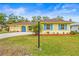 Well-maintained single-story home with lush green lawn, bright blue shutters, and a yellow facade at 2909 Concord St, Sarasota, FL 34231