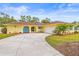 Charming yellow home featuring a large driveway, manicured lawn, and bright blue arched front door and shutters at 2909 Concord St, Sarasota, FL 34231