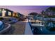 Home's backyard showcases a boat dock with boat lift and waterside patio, illuminated with landscape lighting at 303 Bryn Mawr Is, Bradenton, FL 34207