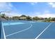 Full view of a blue outdoor basketball court surrounded by trees and tennis courts at 303 Bryn Mawr Is, Bradenton, FL 34207