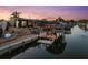 Waterfront home featuring a private dock with a boat lift and outdoor entertaining space at dusk at 303 Bryn Mawr Is, Bradenton, FL 34207