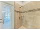 Tiled shower with glass door and shower head; an exterior door with blinds is visible at 322 Langholm Dr, Venice, FL 34293