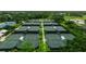 Aerial view of well-maintained tennis courts nestled in a lush, green setting, offering a perfect spot for recreation and exercise at 322 Langholm Dr, Venice, FL 34293