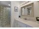 Bright bathroom with a decorative framed mirror, vanity, and a shower with a nautical-themed curtain at 3235 Gulf Of Mexico Dr # A305, Longboat Key, FL 34228