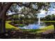 Scenic view of a pond with a fountain, surrounded by mature trees and lush green space at 349 Blackbird Ct, Bradenton, FL 34212