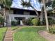 Two story condo with red tile roof, green lawn, and mature trees in a lush landscaped setting at 3500 El Conquistador Pkwy # 129, Bradenton, FL 34210