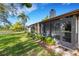 View of backyard with screened-in porch, door, green grass, palm trees and pond in the distance at 4463 Atwood Cay Pl # 22, Sarasota, FL 34233